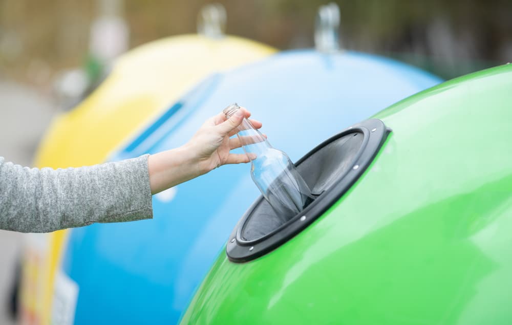 a person placing a bottle in a recycling bin 01
